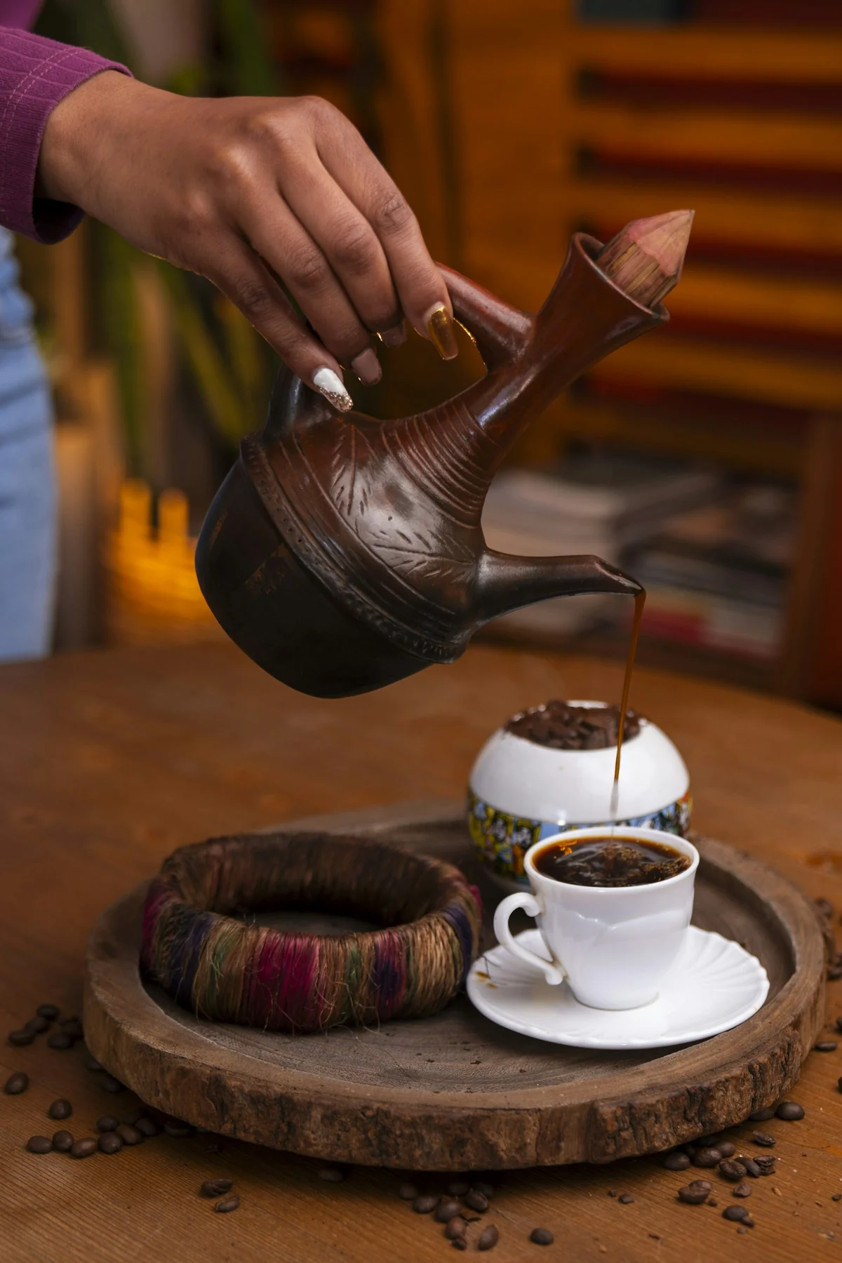 Coffee pouring from a clay jebena into a small white cup