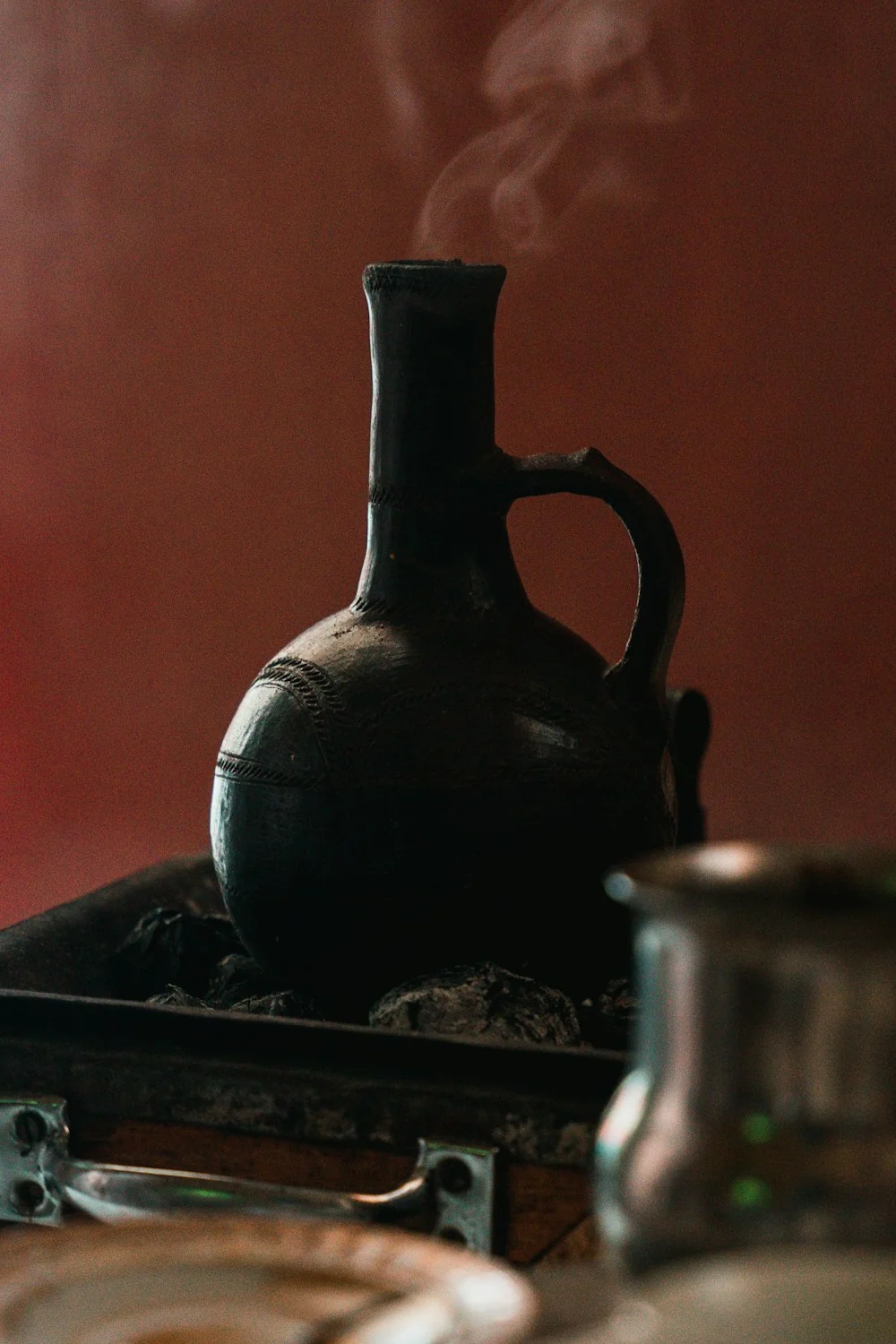 A black clay jebena warming over a stove